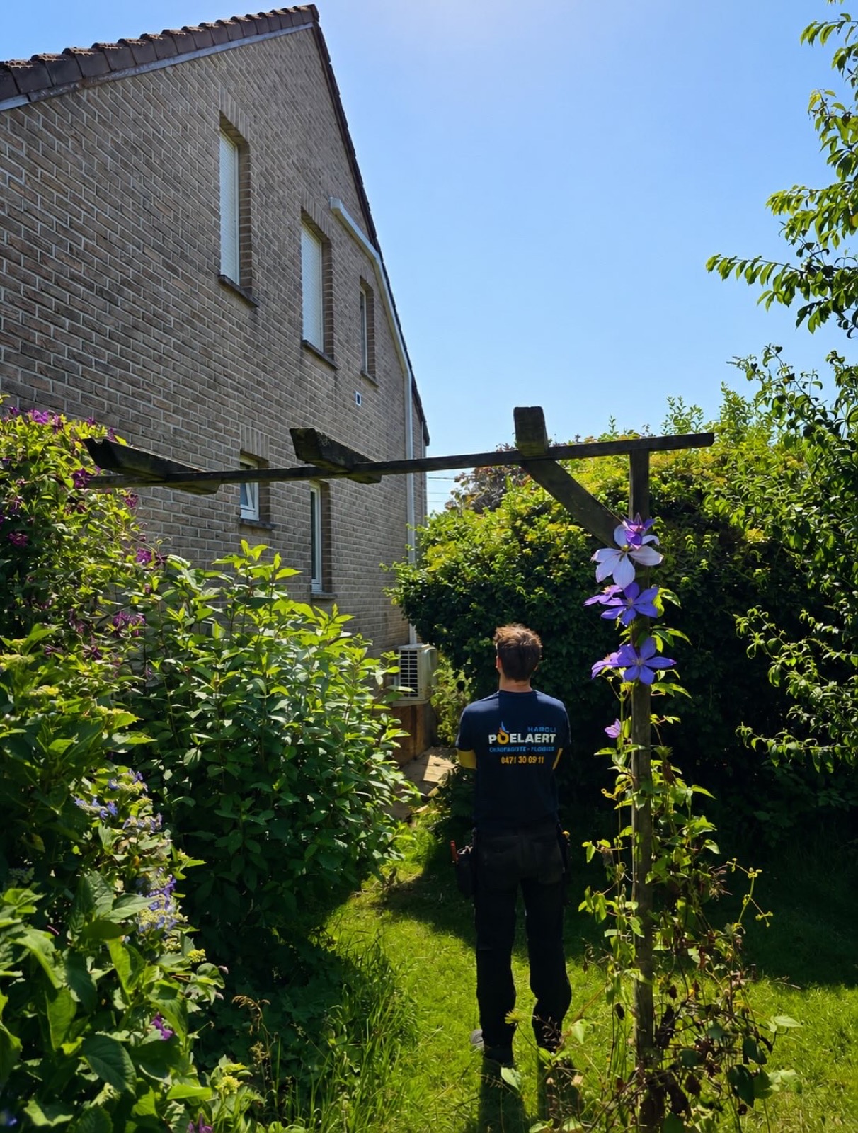 Le technicien dans le jardin devant la maison familiale à Genappe avant la pose de la climatisation