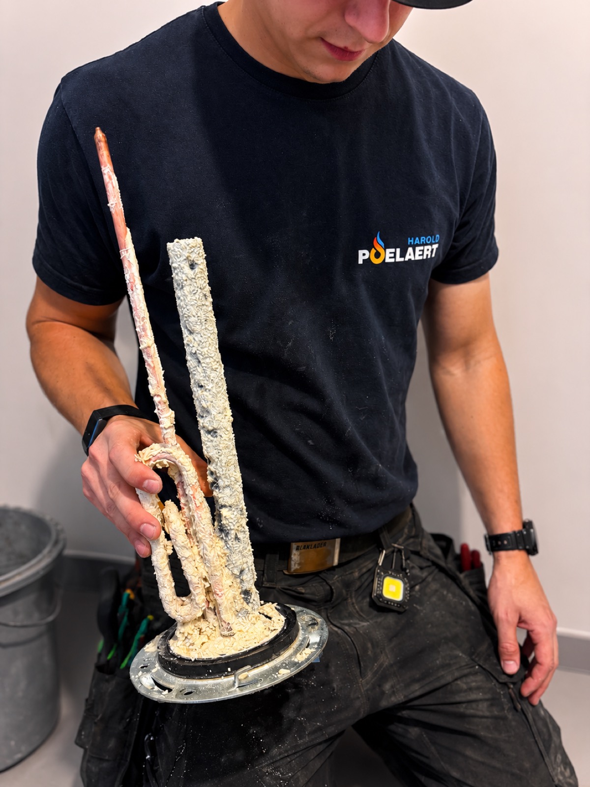 Ancienne résistance de boiler entièrement entartrée, tenue à la main avant remplacement