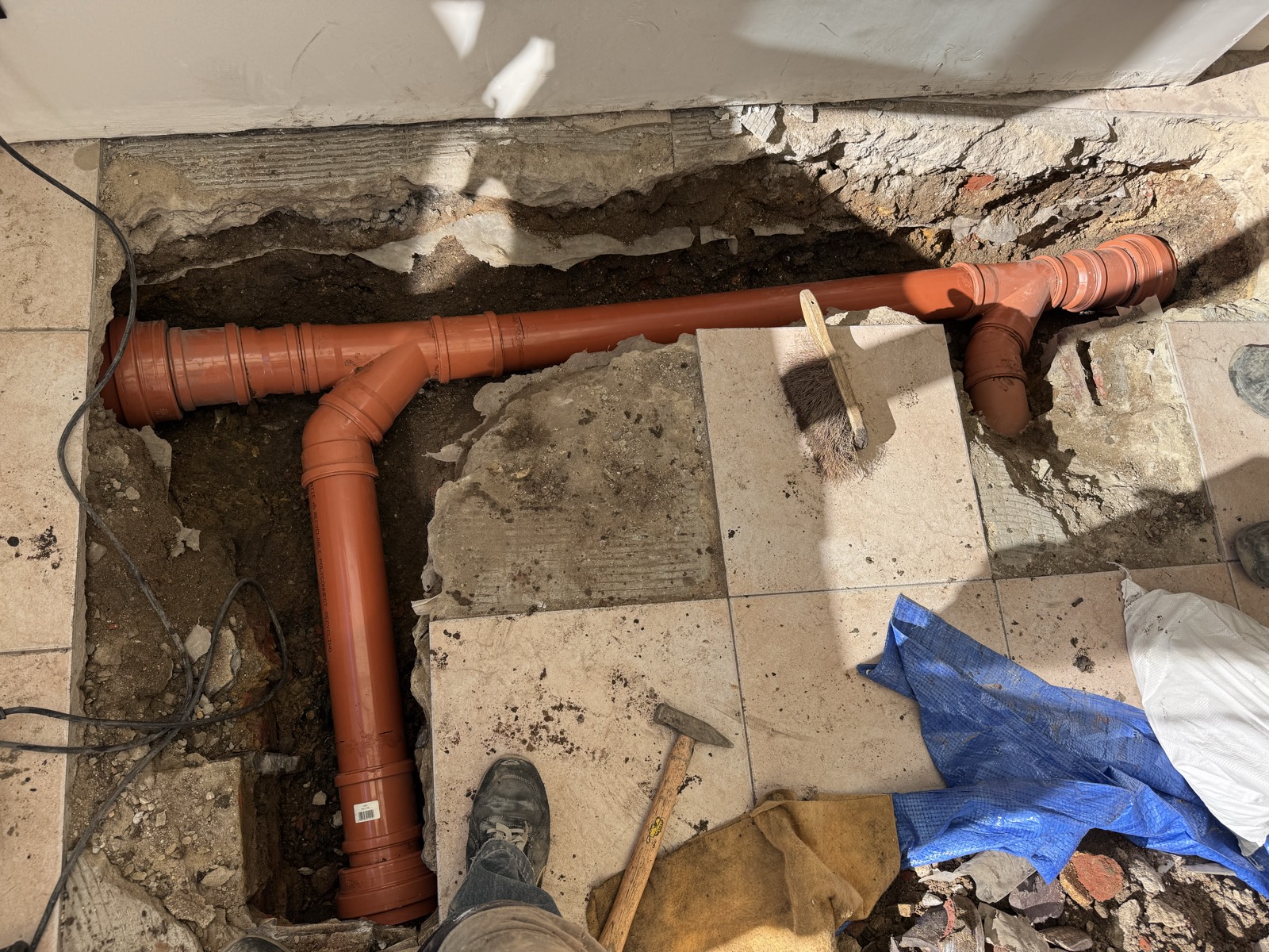 Nouvelle canalisation d'évacuation en PVC orange diamètre 110 posée dans la tranchée ouverte au sol