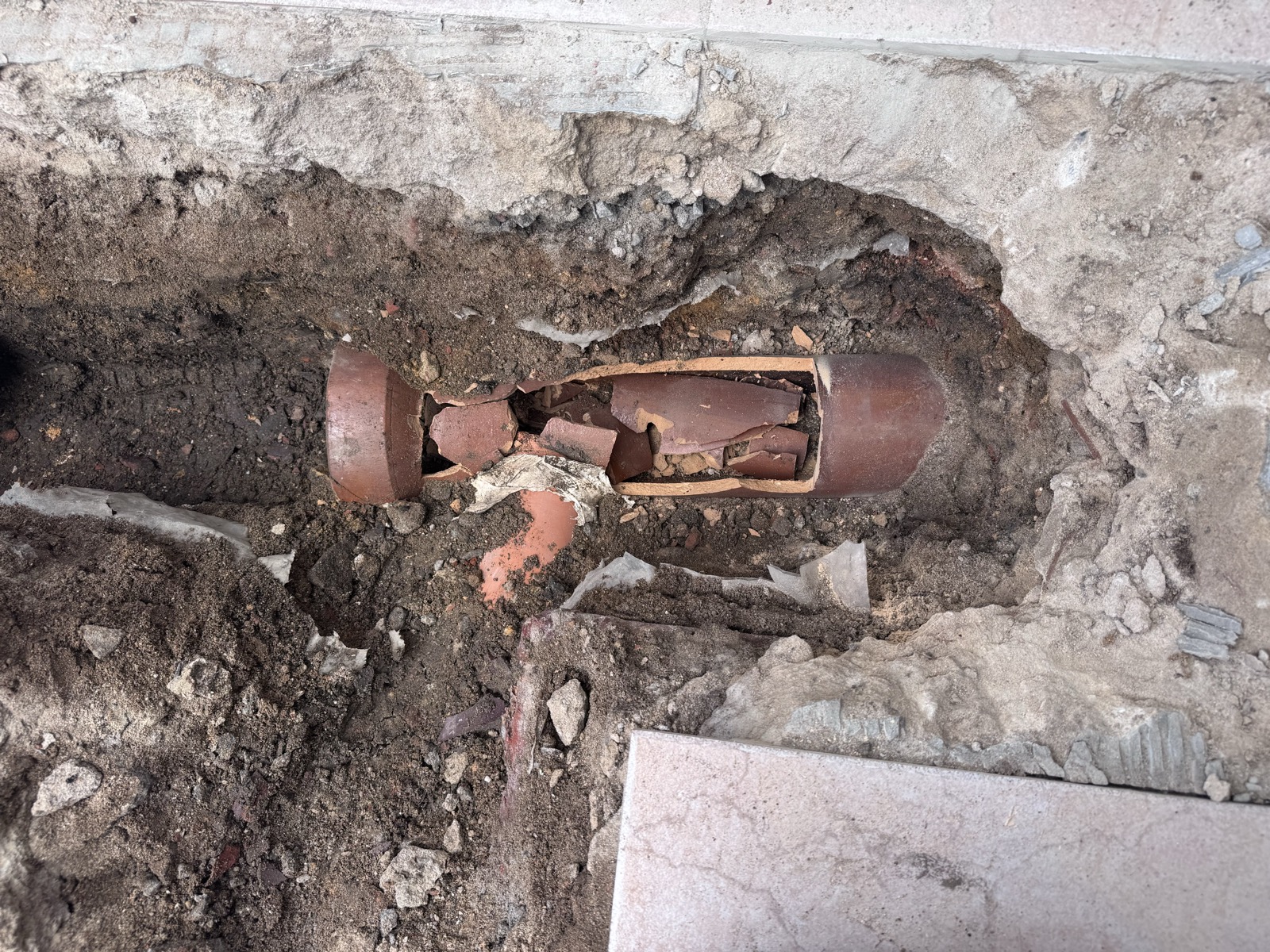 Ancienne canalisation en grès entièrement cassée, tuyau fendu et rempli de débris le long du réseau