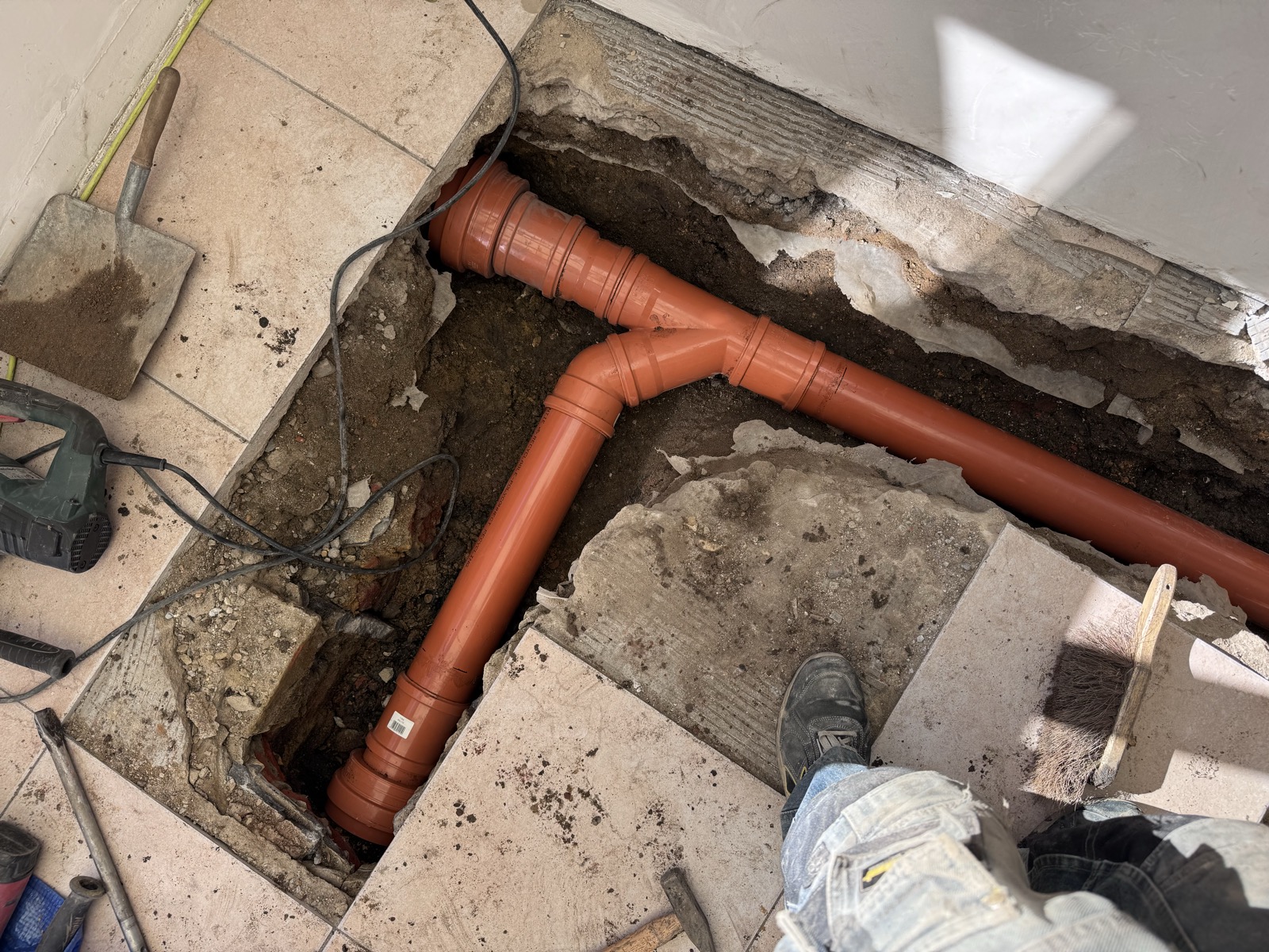 Nouvelle canalisation en PVC orange diamètre 110 avec coude et raccord en Y posée dans la tranchée