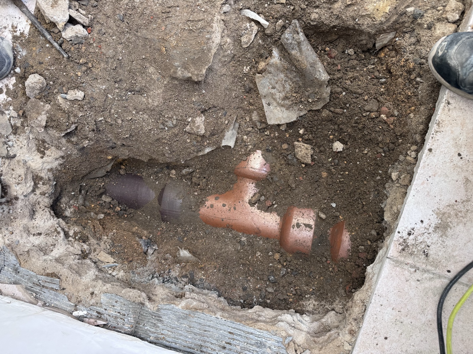 Ancien piquage en PVC raccordé au tuyau en grès, dégagé sous le carrelage déposé